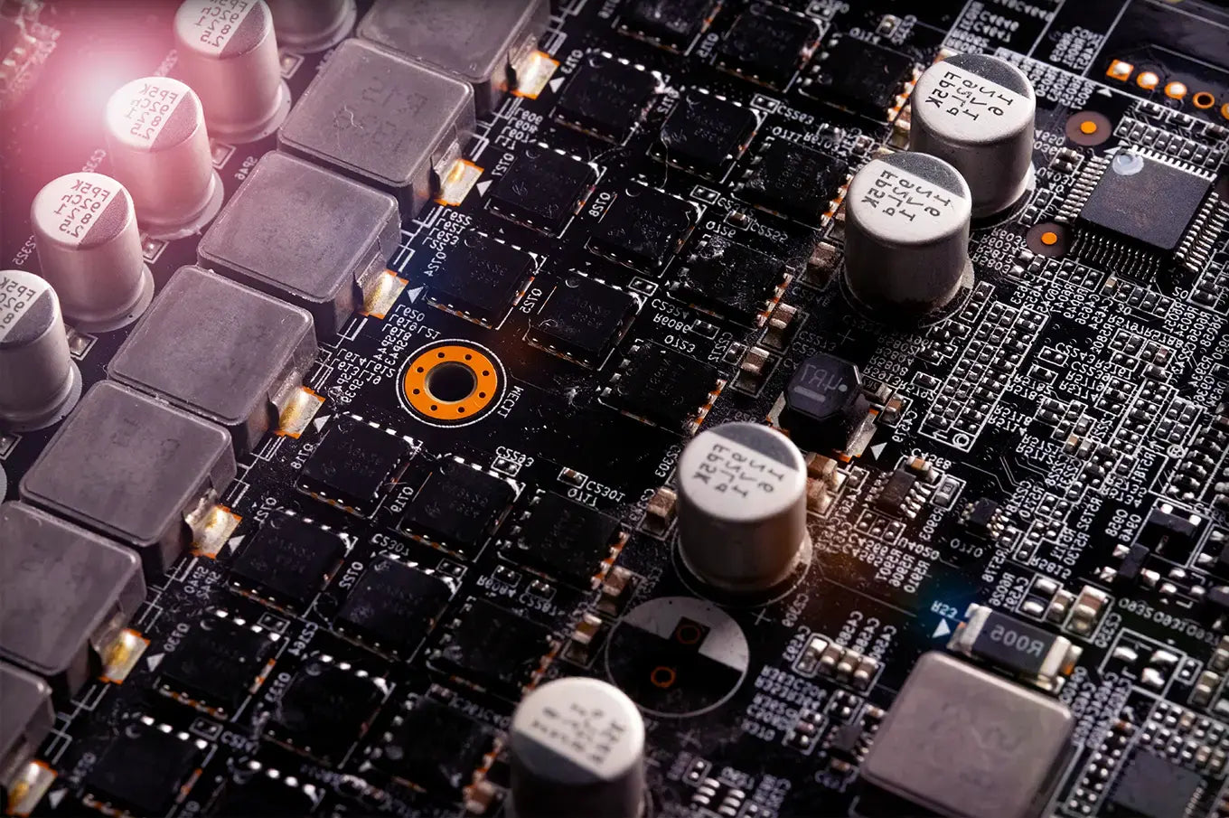 Close-up of a gaming PC motherboard showing capacitors, chips, and power circuitry, showing components that can cause coil whine