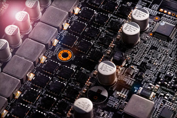 Close-up of a gaming PC motherboard showing capacitors, chips, and power circuitry, showing components that can cause coil whine